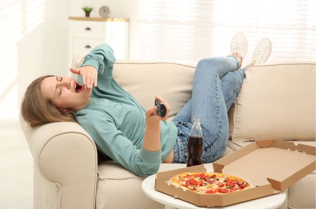 persona sul divano che mangia la pizza